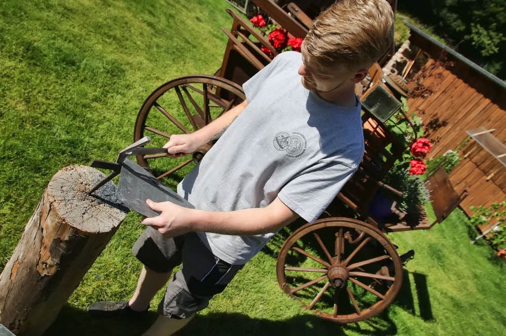 Julian Seibert bearbeitet mit dem Schieferhammer eine Platte.
