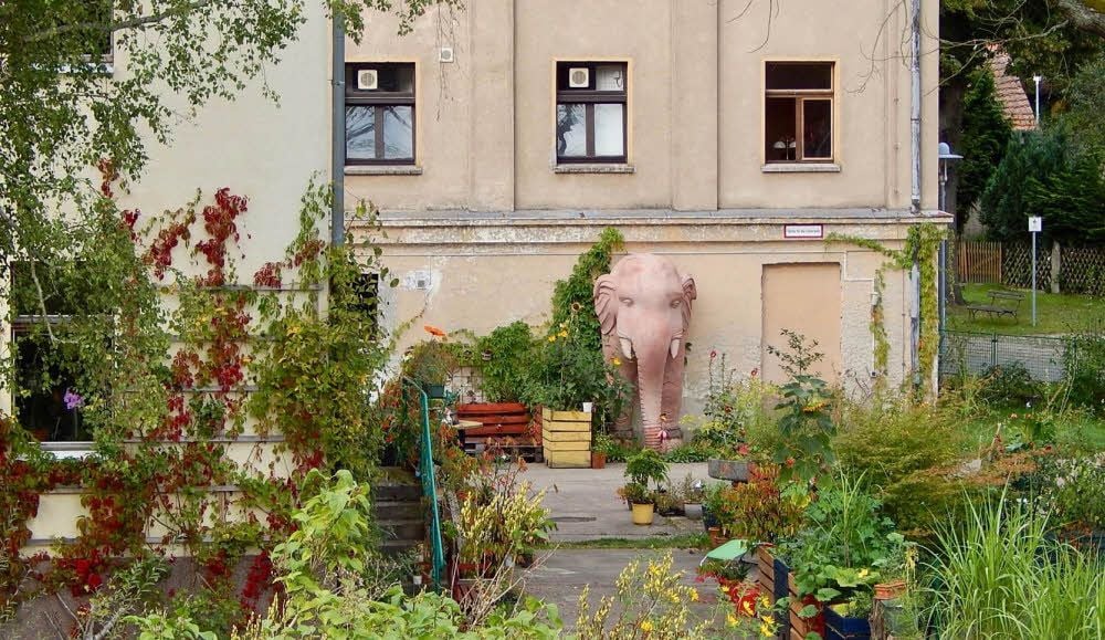 Eine Ansicht aus wärmeren Tagen - mit einem der herrlich irritierenden Elefanten vor dem Haus, die in der Deutschen Oper Berlin ausgemustert und von Tilman Kunowski aufs Land geholt worden sind.