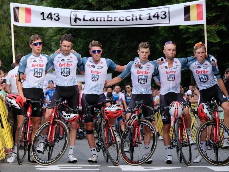 Die Fahrer des Teams Lotto Soudal stehen für eine Schweigeminute zum Tod von Bjorg Lambrecht mit Trauerflor vor einem Banner. Foto: Hanna Bardo/PAP