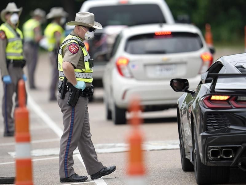 Polizisten kontrollieren kontrollieren Autofahrer bei der Einreise von Louisiana nach Texas, um zu überprüfen, ob diese sich in eine 14-tägige Selbstquarantäne begeben müssen. Foto: David J. Phillip/AP/dpa