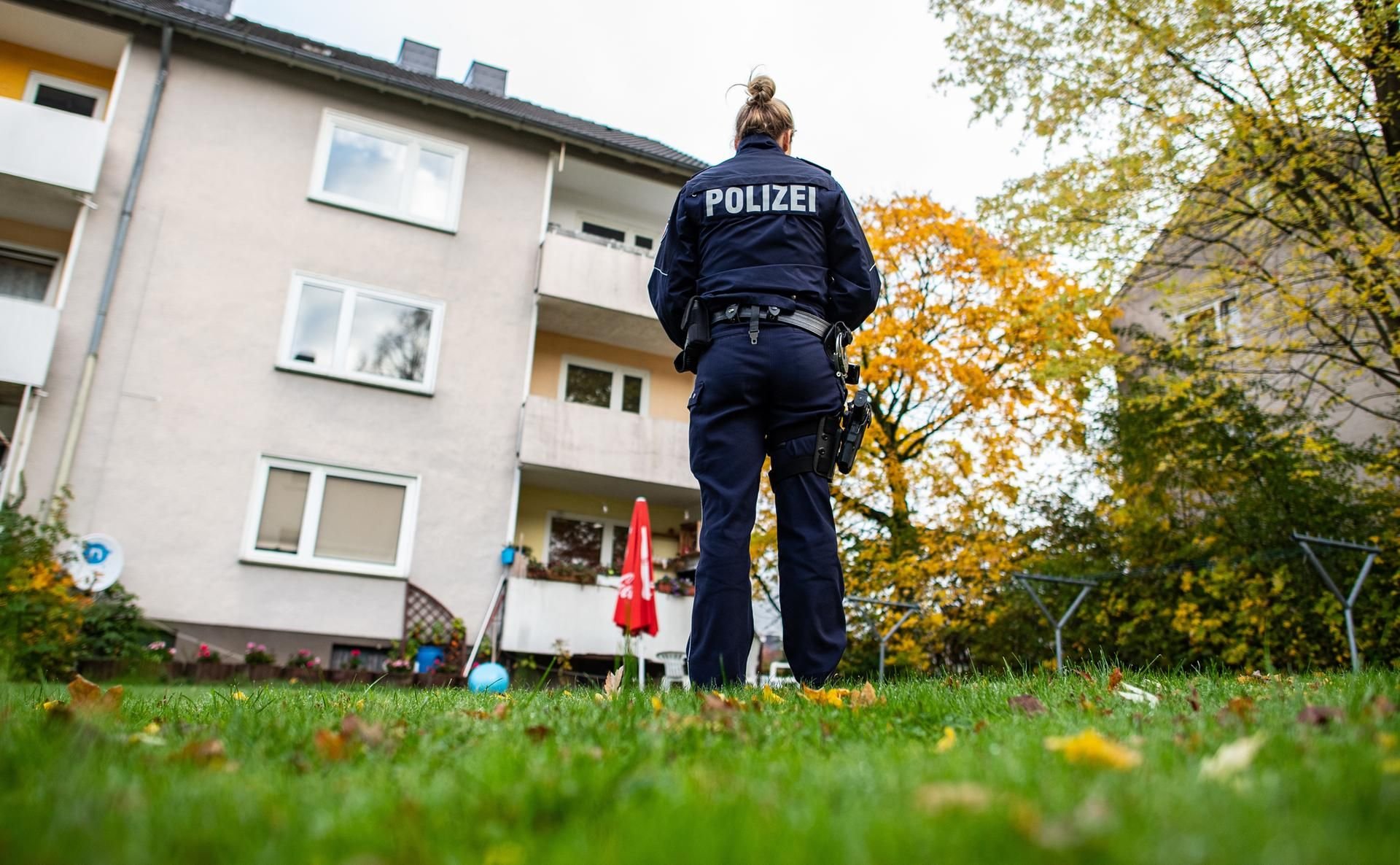 Eine Polizistin steht im Garten des Mehrfamilienhauses, in dem eine 15-Jährige ihren Bruder getötet haben soll.