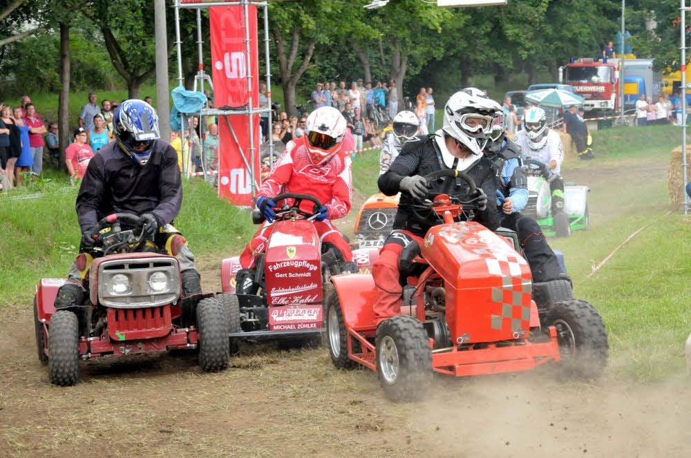 Männer fahren ein Rennen mit umgebauten Rasentraktoren.