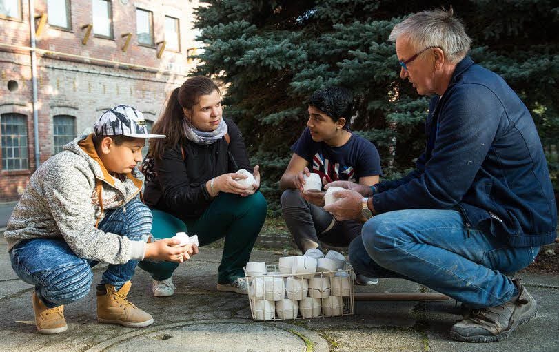 Georgi aus Bulgarien, Pädagogin Nicole Haufe und Nawras aus Syrien lassen sich von Siegfried Kramer (v.l.) den Aufbau einer Gussform erklären.