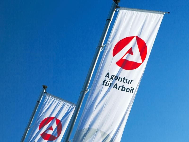 Fahnen der „Agentur für Arbeit” wehen im Wind. Foto: Jens Büttner/Archiv