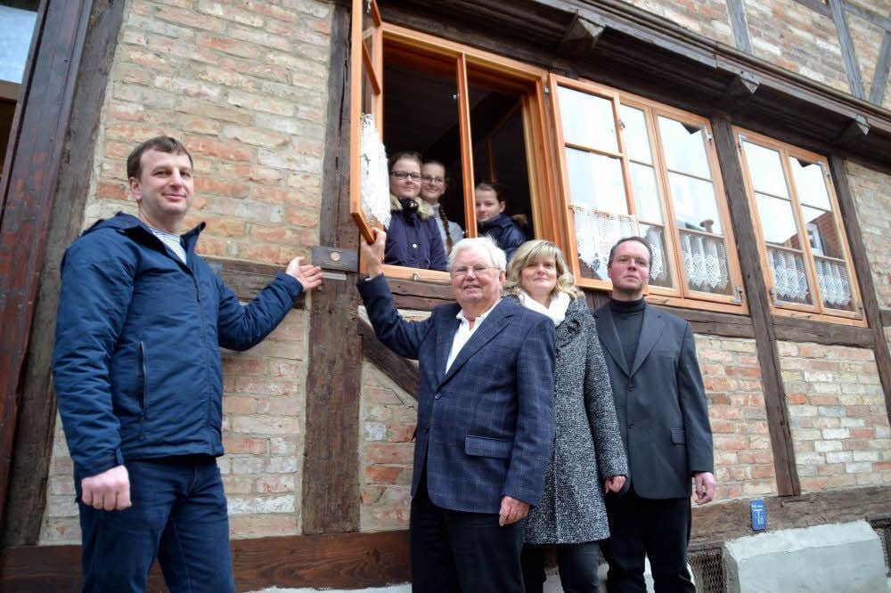 Das Haus Augustinern 75 in Quedlinburg ist saniert. Darüber freuen sich Besitzer Eduard Reger (links) und seine Töchter (im Fenster) sowie Petra Gennari von der Stadt und Ortskurator Claus Mangels.