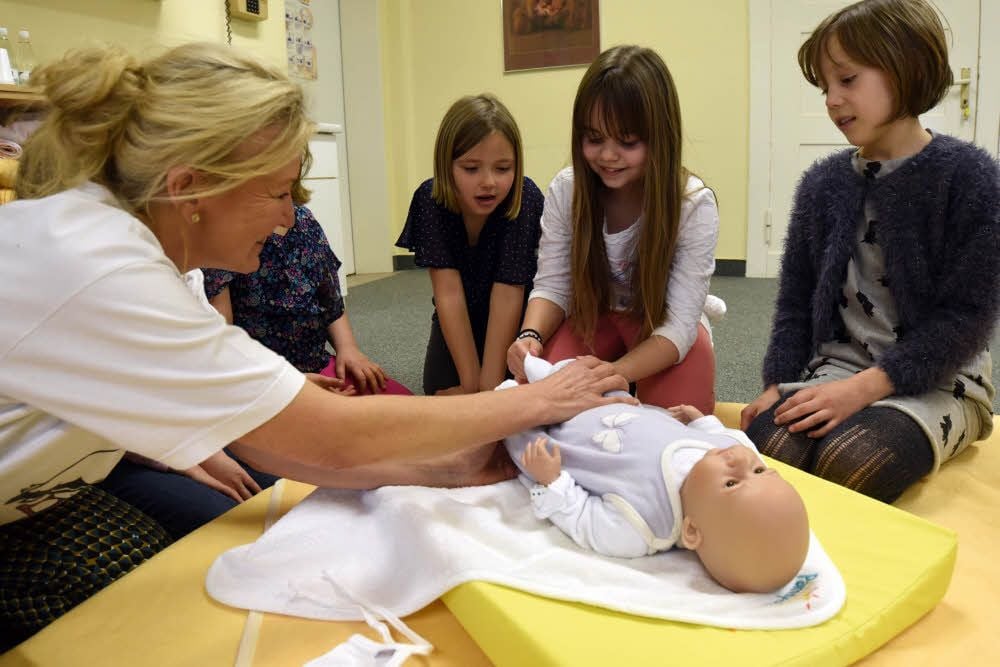 Wie zieht man Babys an? Katrin Herrmann zeigt es den Kindern.
