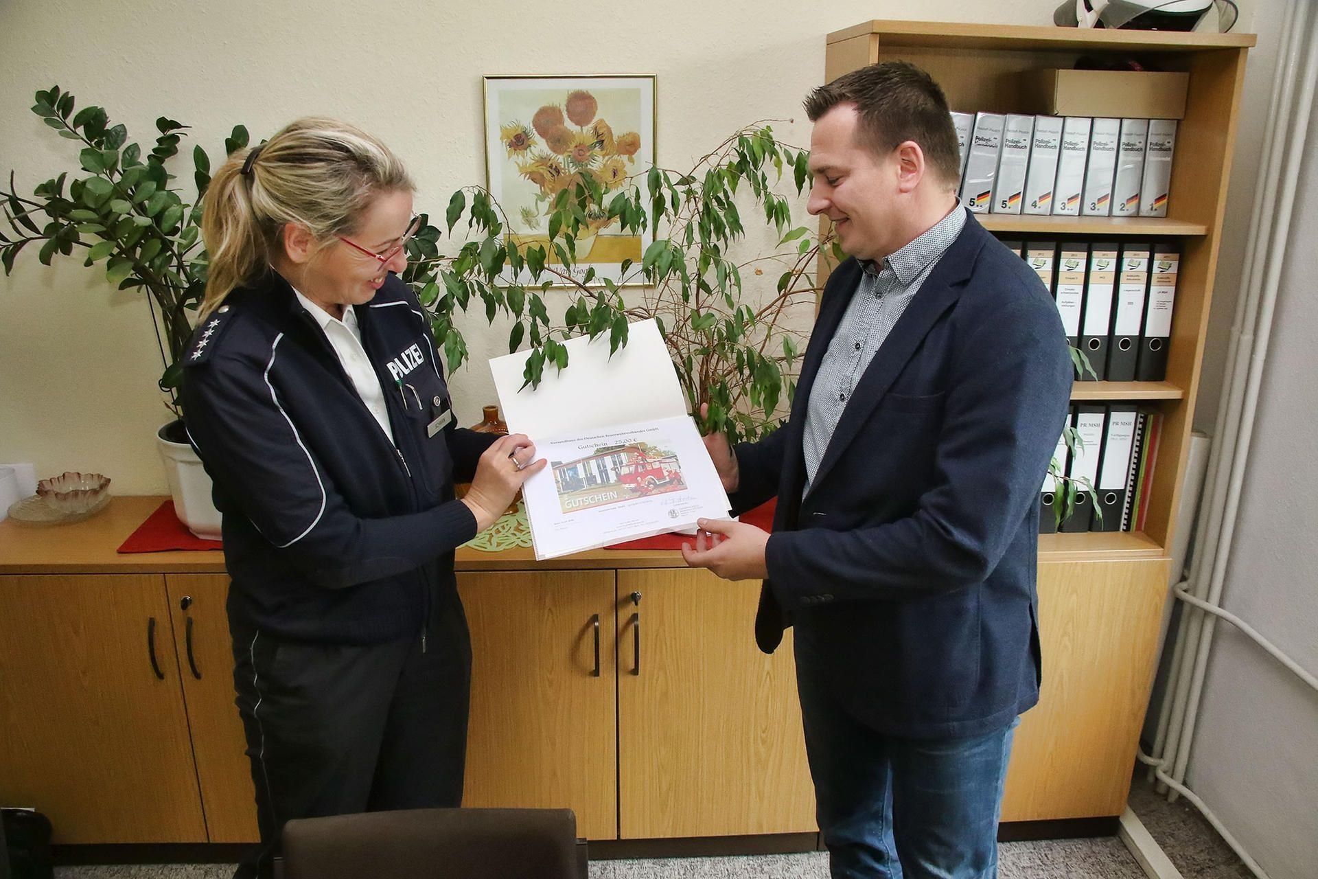 Polizeisprecherin Steffi Schwan übergibt Steffen Reise für seine Zivilcourage eine kleine Aufmerksamkeit.