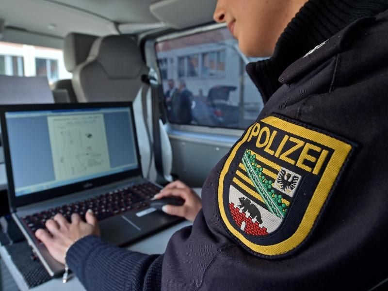 Ein Polizist schreibt an einem Laptop in einem Streifenwagen.