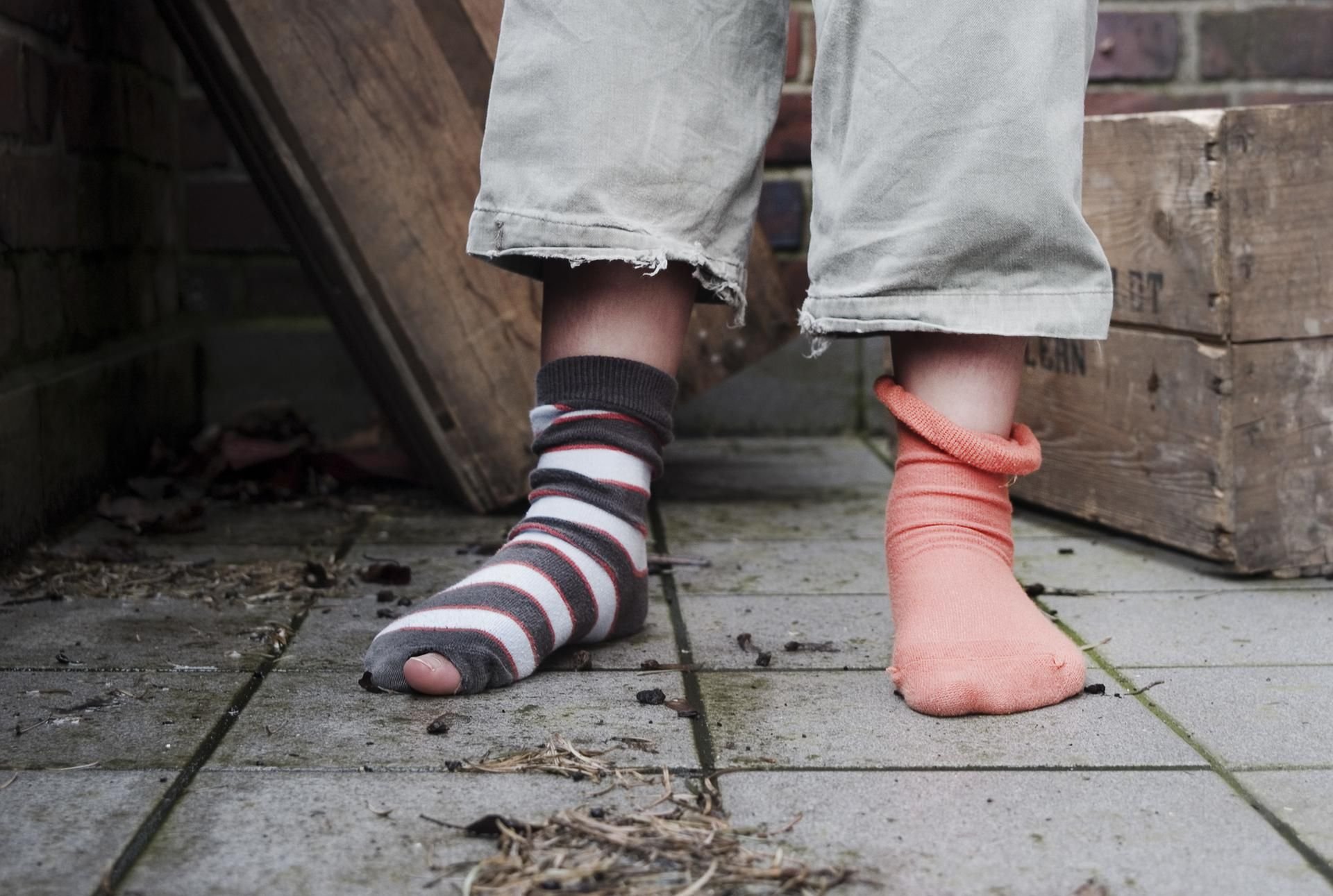 Ein zehn Jahre altes Mädchen steht in abgetragener Kleidung ohne Schuhe in einem Hinterhof. Nicht jedes Kind hat die gleichen Chancen.