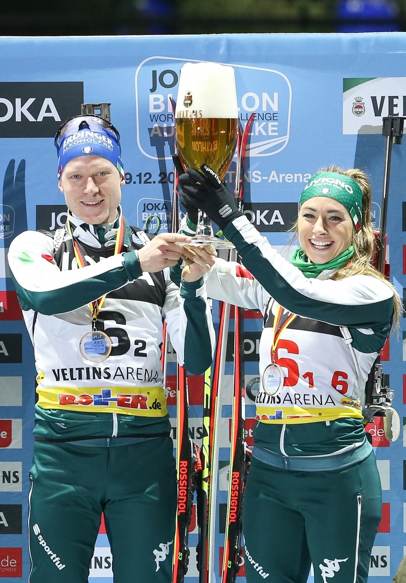 Die italienischen Biathleten Lukas Hofer (l-r) und Dorothea Wierer feiern den Sieg mit einem Glas Bier bei der 17. Biathlon World Team Challenge (WTC) in der Veltins-Arena. Der Sieger aus zehn gemischten Zweierteams aus verschiedenen Nationen wird durch ein Massenstartrennen und einen anschließenden Verfolgungswettbewerb ermittelt.