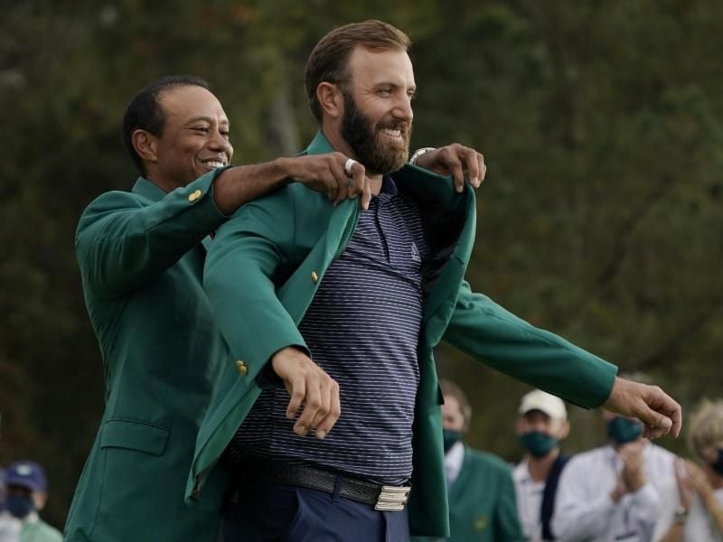 Masters-Champion Dustin Johnson (r) bekam von Vorjahressieger Tiger Woods das grüne Jackett angezogen. Foto: Charlie Riedel/AP/dpa