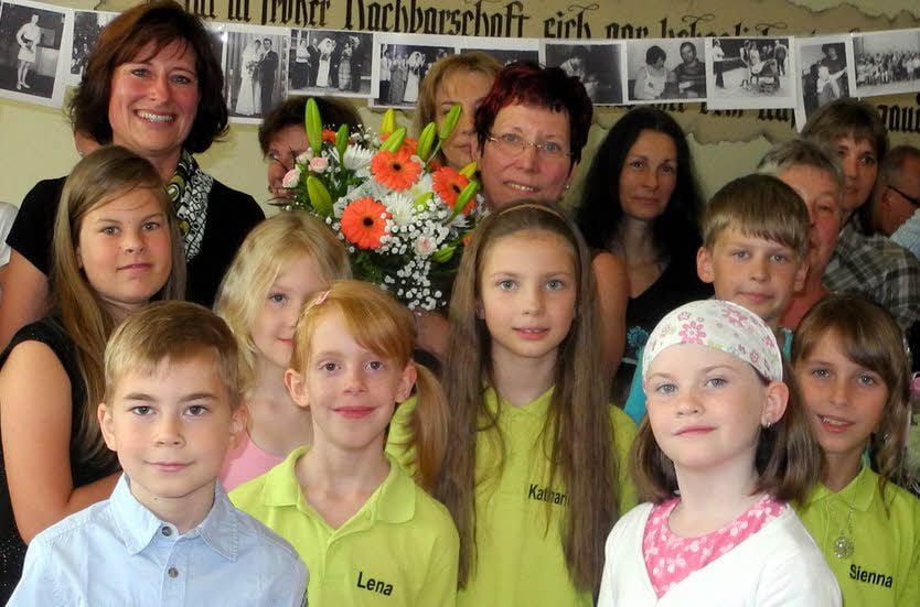 Eine völlig überraschte Petra Lehmann wird in der Evangelischen Grundschule Holzdorf von vielen Gratulanten umringt.