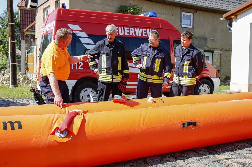 Jens Kunze demonstriert einigen Mitgliedern der Feuerwehr, wie das Schlauchsystem auf- und wieder abgebaut wird.