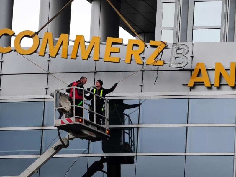 Arbeiter demontieren den Schriftzug an einer Commerzbankfiliale. Foto: Daniel Reinhardt/dpa/Archivbild