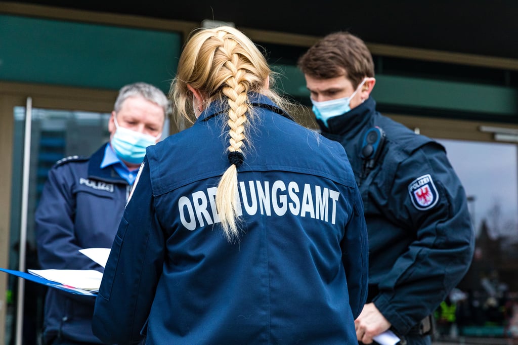 01.03.2021, Brandenburg, Cottbus: Einsatzkräfte vom Ordnungsamt und Polizei besprechen sich vor dem Einsatz auf dem Stadthallenvorplatz. Wegen der Entschärfung einer Weltkriegsbombe ist am Montagmorgen ein Teil der Cottbusser Innenstadt evakuiert worden. Rund 3700 Menschen waren aufgerufen, das Areal rund um den Fundort in der Virchowstraße zu verlassen. (zu "Bombe in Cottbuser Innenstadt wird entschärft - Evakuierung begonnen") Foto: Frank Hammerschmidt/dpa-Zentralbild/ZB - Honorarfrei nur für Bezieher des Dienstes ZB-Funkregio Ost +++ ZB-FUNKREGIO OST +++