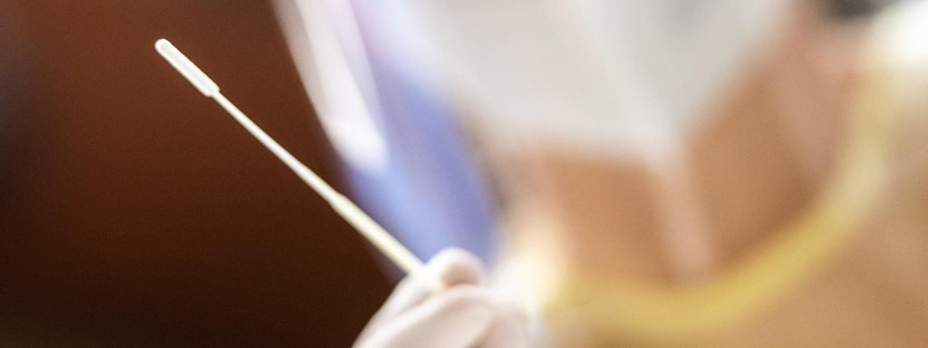 Eine Mitarbeiterin in einem Testzentrum hält ein Stäbchen für einen Rachenabstrich in der Hand.