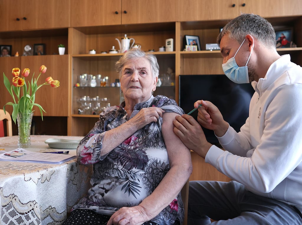 07.04.2021, Sachsen-Anhalt, Schönebeck: Der Hausarzt Robin John verabreicht der 84-jährigen Erika Dressler während eines Hausbesuchs die erste Impfung mit dem Corona-Impfstoff Comirnaty von Biontech/Pfizer. In Sachsen-Anhalt werden die niedergelassenen Ärzte in die Impfstrategie einbezogen.