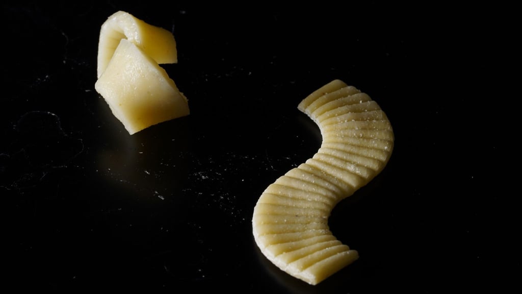 Eine Nudel wird im ungekochten (r) und gekochten Zustand gezeigt. Hierbei handelt es sich um eine Flache Nudel aus dem Forschungslabor, die sich beim Kochen zu in eine dreidimensionalen Form entfaltet hat.