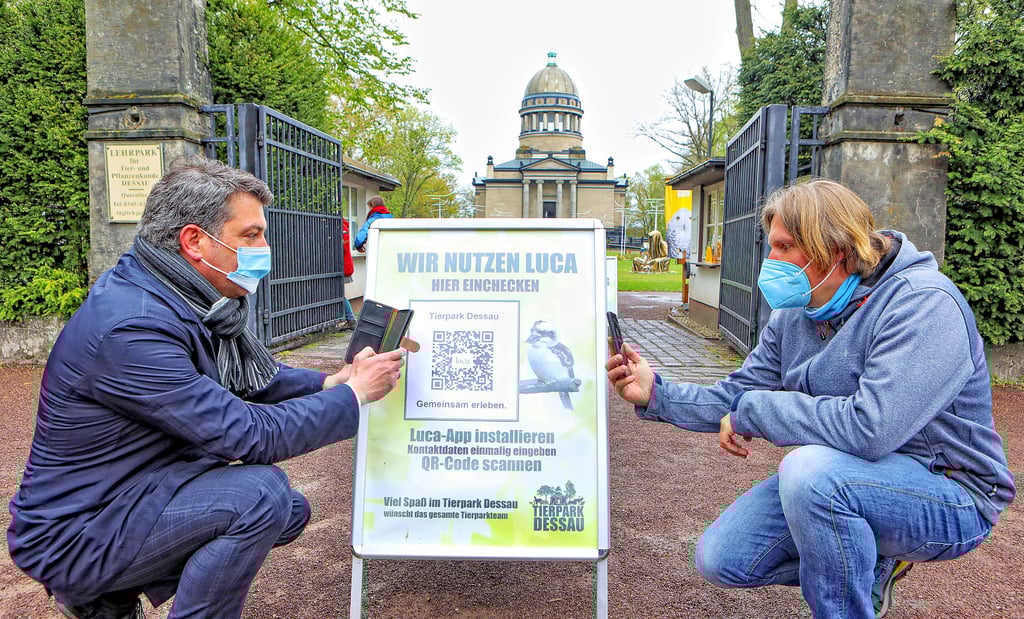 Sozialdezernent Jens Krause (li.) und Tierparkchef Jan Bauer zeigen, wie einfach es ist, die Luca App aufs Handy zu laden.