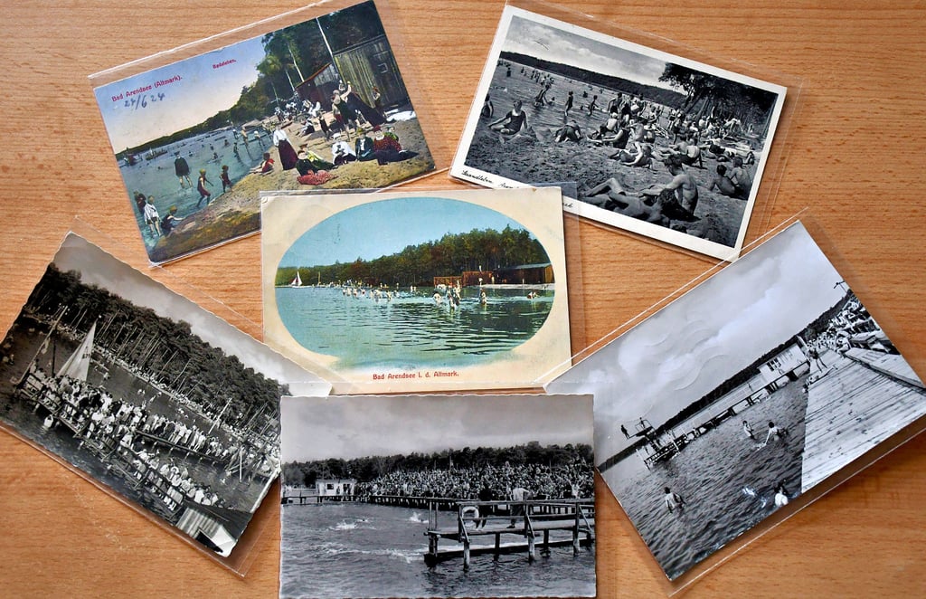 Eine Auswahl von alten Ansichtkarten, die ausschließlich das Gelände des heutigen Strandbades zeigen. Die auf diesem Foto älteste Karte (verschickt 1911) befindet sich in der Mitte. Daneben liegen Exemplare aus den 1920er (oben von links) und 1930er Jahren sowie aus den 1950er (unten von links) 1960er und 1980er Jahren.