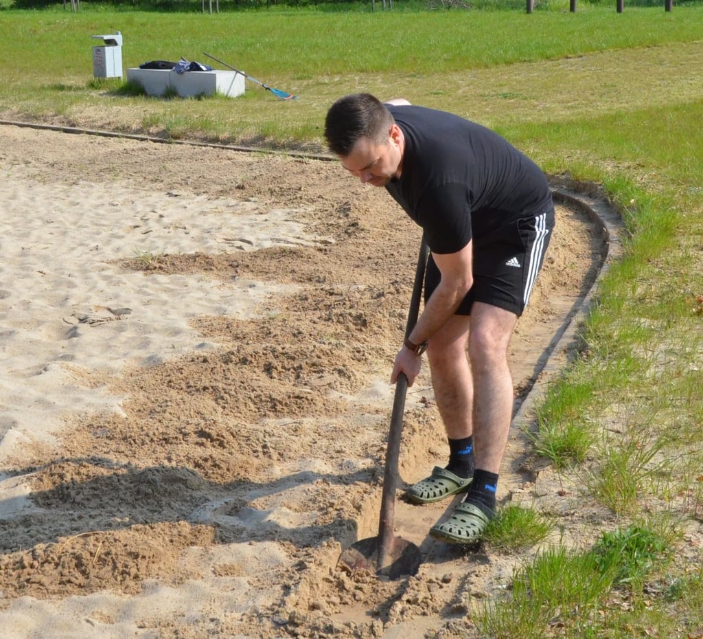 Organisator Jan Seidel säubert die Kante am Badestrand vom Sand.