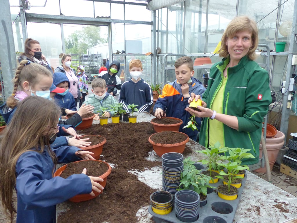 Marianne Wilz zeigt den Kindern aus dem Hort Möser, wie Pflanzen eingetopft werden.