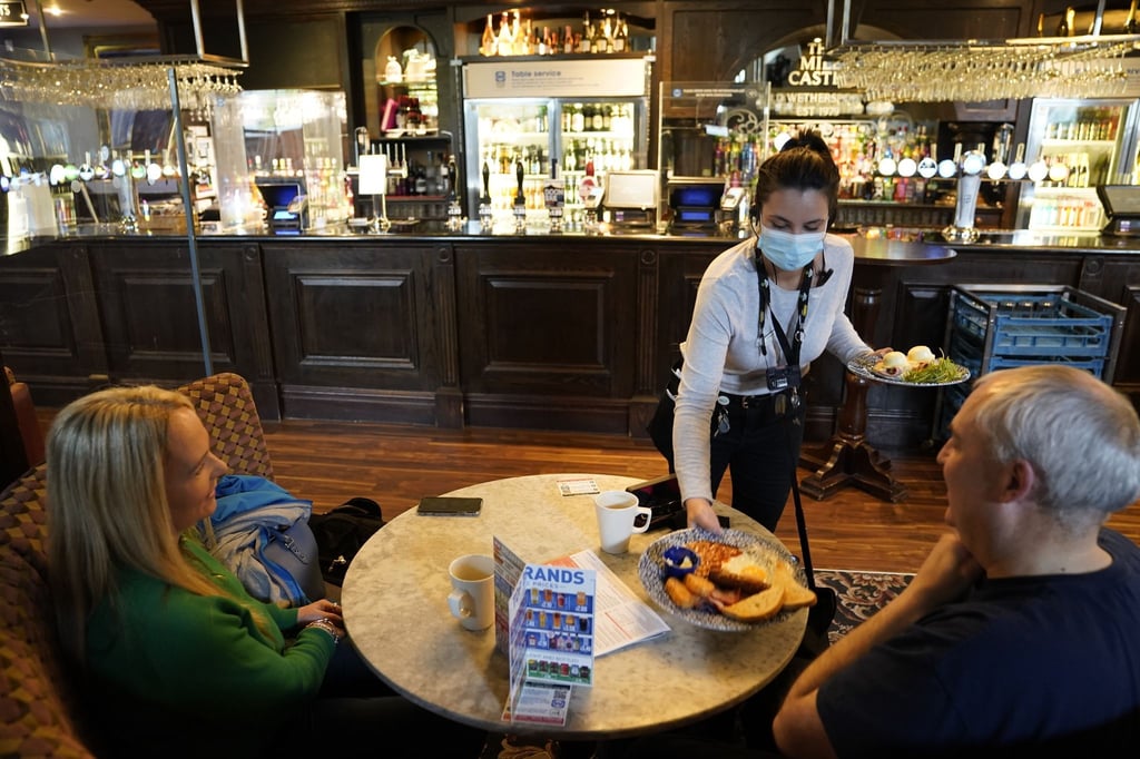 Eine Kellnerin bringt zwei Gästen in einem Pub in Newcastle eine Mahlzeit an den Tisch.