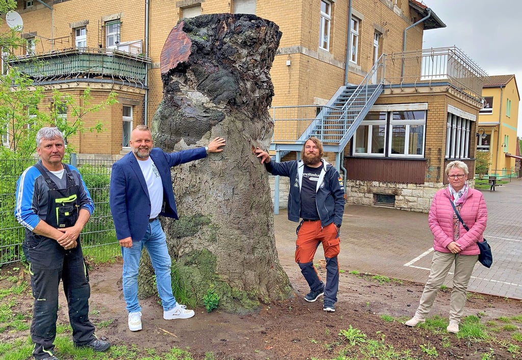 Gerald Reichmann (v.l.n.r.), Sponsor Sören Lorenz, Kettensägenschnitzer Sebastian Seiffert und Schulleiterin Konstanze Naundorf am Stamm, der schon bald ein Kunstwerk sein wird.