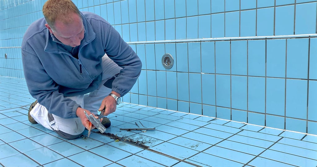Martin Kahle prüft die Fliesen im Freibad Altenbrak. Lockere und beschädigte Teile entfernt er.