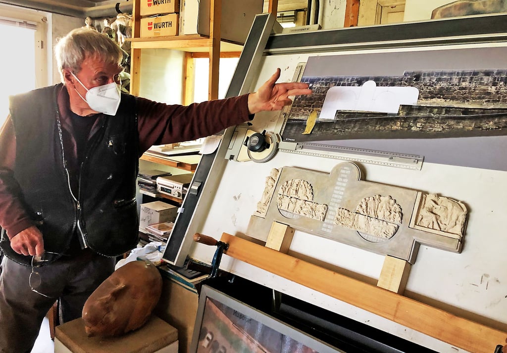 Wolfgang Dreysse erläutert in seinem Atelier den Entwurf des Reliefs, das an der Sandsteinmauer im sogenannten Zwingergang, dem Aufgang auf dem Stiftsberg, seinen Platz finden soll.