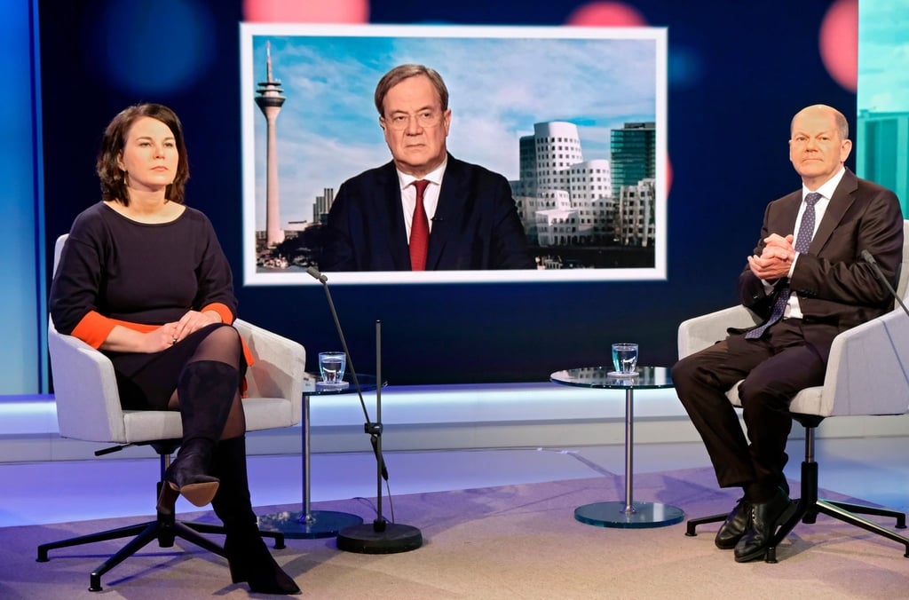Unions-Kanzlerkandidat Armin Laschet wird auf einem Fernsehschirm gezeigt, während die Mitbewerbern von Grünen und SPD, Annalena Baerbock und Olaf Scholz im Fernsehstudio bei einer Diskussionsrunde des WDR-Europaforums in Berlin sitzen.