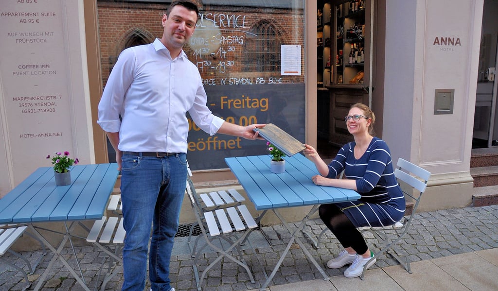 Eine solche Szene könnte es für Passanten vielleicht bald wieder öfters zu sehen geben. Felix Goder vom Restaurant ?Mainly Stendal? in Stendal überreicht einem ?Gast? (einer Mitarbeiterin) im Außenbereich die Speisekarte.