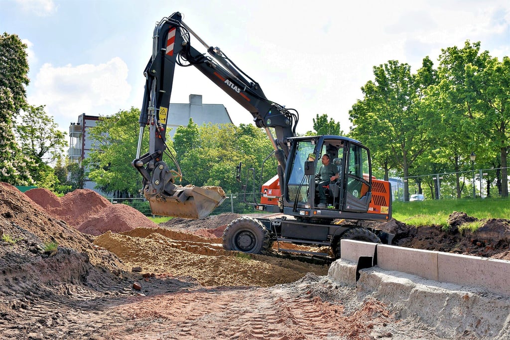 Ein Bagger schaufelt Sandmassen für den neuen Spielplatz an der Berliner Chaussee. Seit Anfang Mai wird hier gebaut.