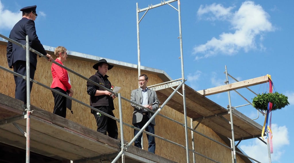 Der Richtkranz kündet von einer weiteren Bauetappe am Rohrsheimer Feuerwehrhaus. Von links: Ortswehrleiter Felix Böhm, Bürgermeisterin Ingeborg Wagenführ, Zimmerermeister Clemens Esche, der den Richtspruch hält, und Ortsbürgermeister Hans-Jörg Gifhorn, der zuvor den letzten Nagel ins Holz eingeschlagen hatte.