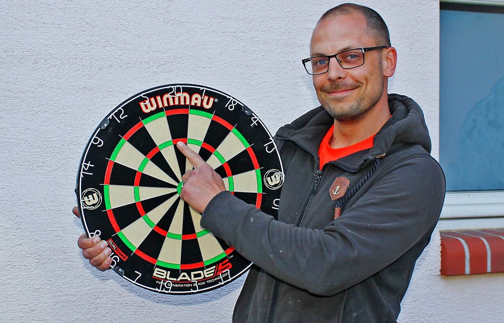 Alexander Kralisch deutet auf die Triple 20 des neuen Dartboards.