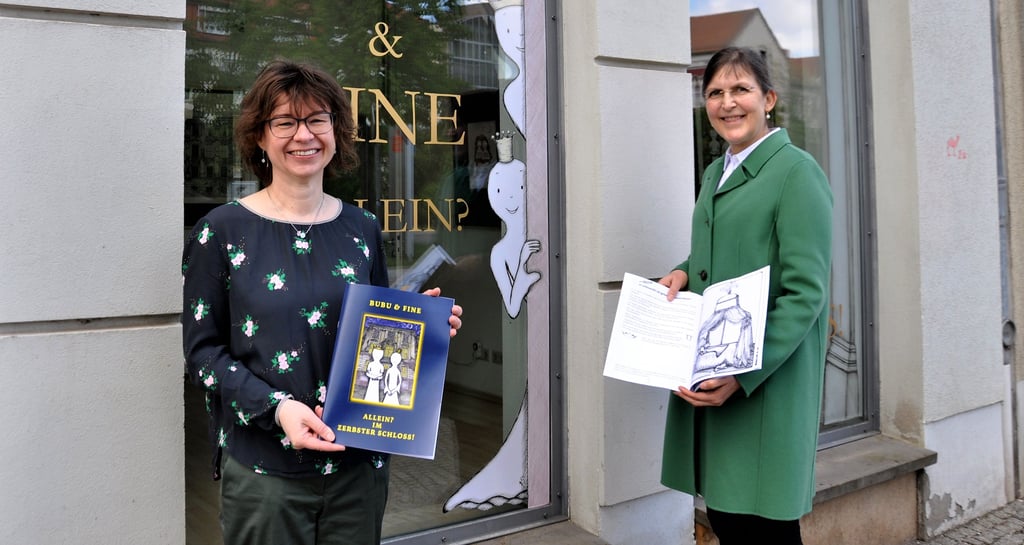 Jana Reifarth (l.) vom Vorstand des Fördervereins Schloss Zerbst und Künstlerin Simone Runge präsentieren das fertigte Erzählheft zum Ausmalen über die beiden Schlossgeister Bubu und Fine.