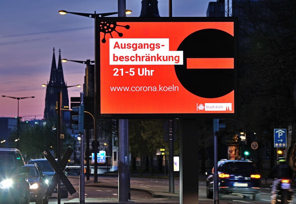 Eine Anzeigetafel in Köln weist Ende April auf die Ausgangsbeschränkung zwischen 21:00 und 05:00 Uhr hin.