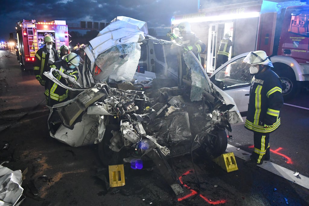 Kräfte der Feuerwehr stehen am zerstörten Unfallwrack.