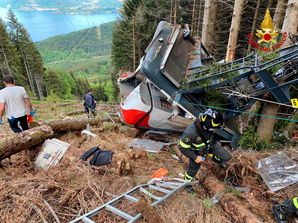 Rettungskräfte arbeiten am Wrack einer abgestürzten Gondel, die in einem Waldstück liegt.
