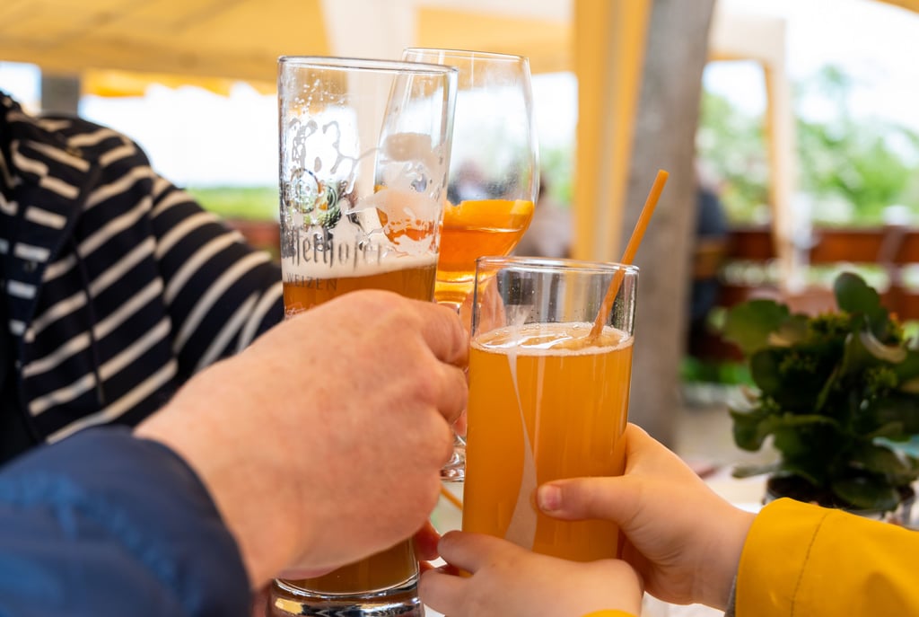 In einem Restaurant stoßen Gäste mit ihren Getränken an.