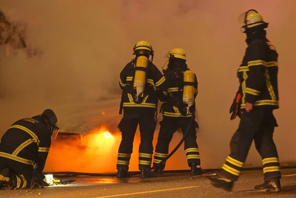 Einsatzkräfte der Feuerwehr löschen ein brennendes Fahrzeug.