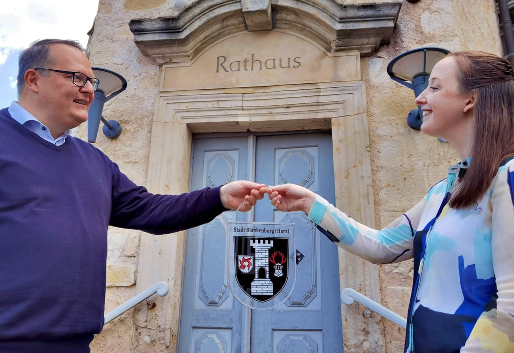 Laura Groom wird von Bürgermeister Heiko Breithaupt in Blankenburg begrüßt. Als Willkommens-Präsent überreichte er der Chiropraktorin ein gläsernes Stadtwappen.