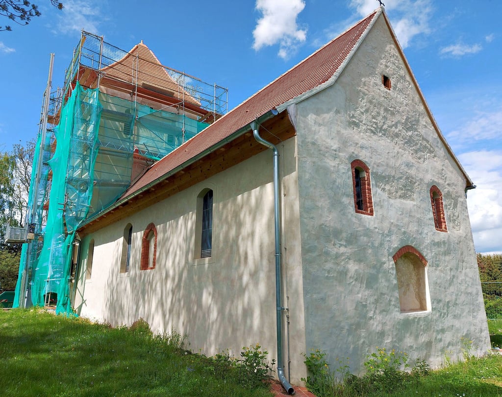 Die Außenhaut der kleinen Dorfkirche von Gersdorf in der Gemeinde Niedere Börde ist schon neu, die Fenster einer Glaskünstlerin eingesetzt, das Dach gedeckt. Bald fällt auch die Rüstung am Turm.