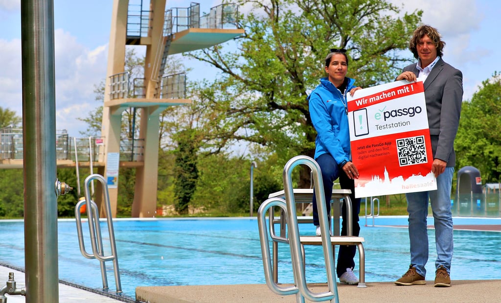 Bäder-Halle-Betriebsleiterin Ulrike Heinicke und DLRG-Landesgeschäftsführer Holger Friedrich stehen im Nordbad in Halle mit dem „ePassGo“-Plakat.
