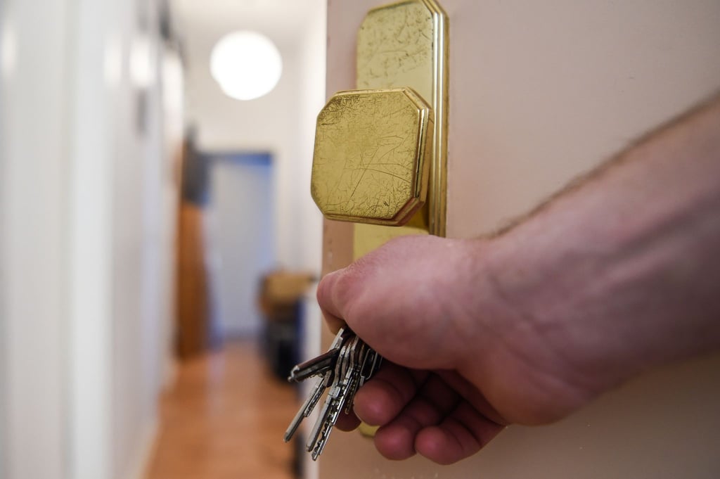 Ein Mann schließt eine Wohnungstür auf und öffnet sie.