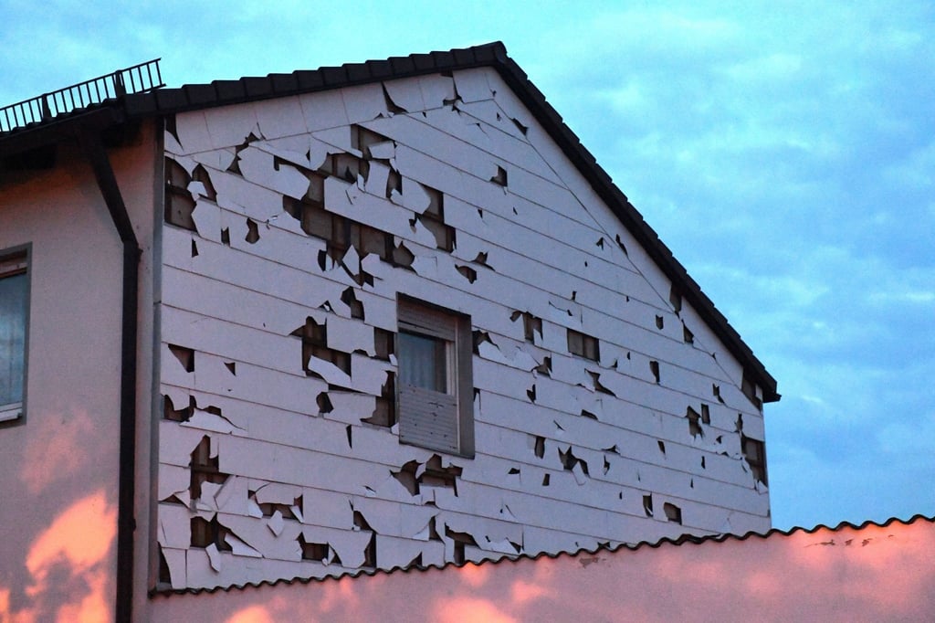 Eine durch Hagel bei einem Unwetter beschädigte Verkleidung einer Hauswand ist zu sehen.