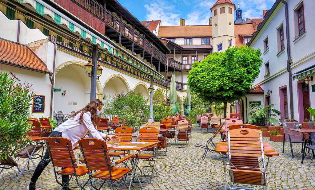 Wiedereröffnung von Restaurants, Vorbereitungen laufen: Auszubildende Eugena Kurmemaj deckt die Tische im Hof des Brauhauses