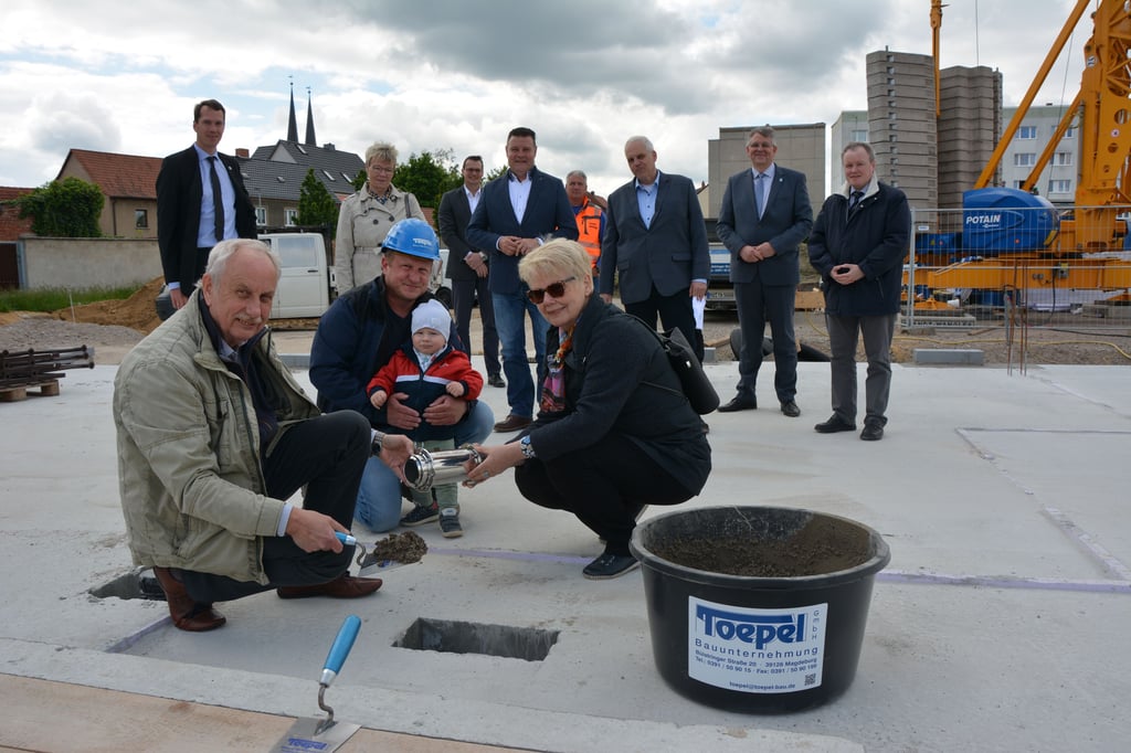 Wenn das keine Symbolkraft hat: Der kleine Arne-Klaas legt mit Papa Andreas Ackermann, der BWG-Aufsichtsratsvorsitzenden Sigrid Schmidt und dem ehemaligen BWG-Vorstand Diethelm Harp den Grundstein für den Neubau an der Martin-Luther-Straße.