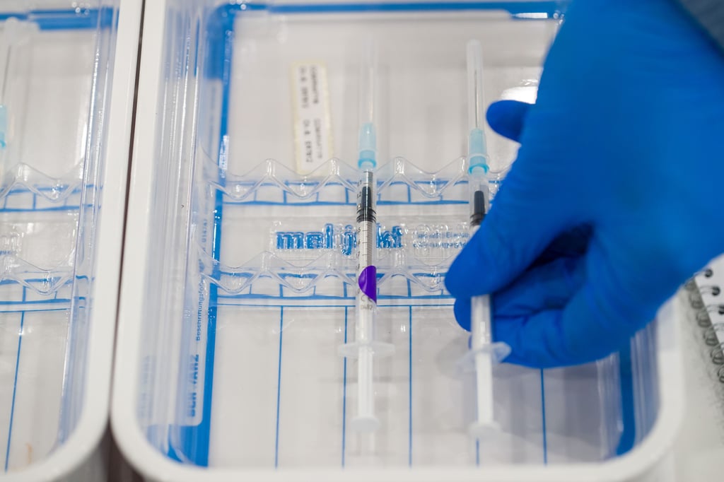 Eine medizinische Fachkraft legt eine aufbereitete Impfspritze mit dem Pfizer-BioNTech-COVID-19-Impfstoff in eine Schale.