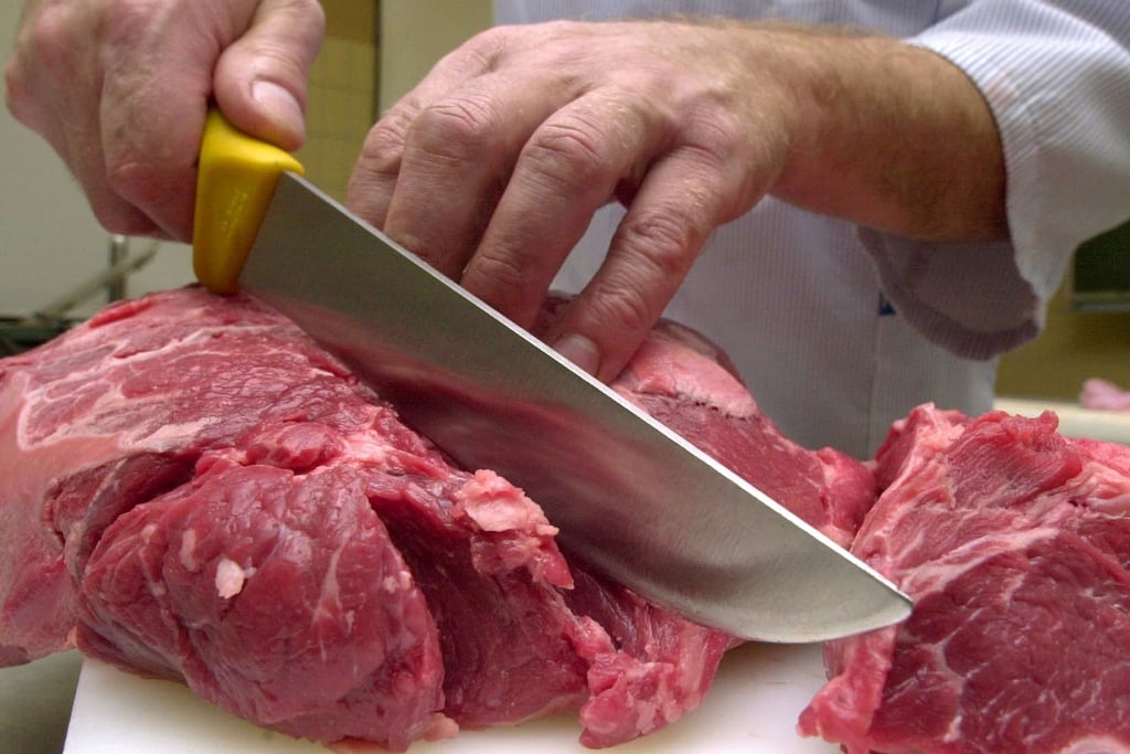 Ein Metzger schneidet Rindfleisch.